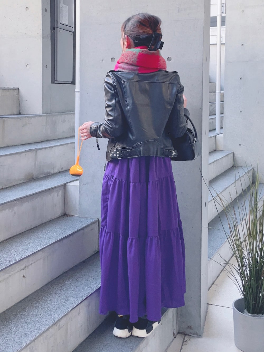 ブラック系のライダースジャケット、パープル系のワンピース、ブラック系のハンドバッグを着用したレディースの秋コーディネートの3枚目の写真
