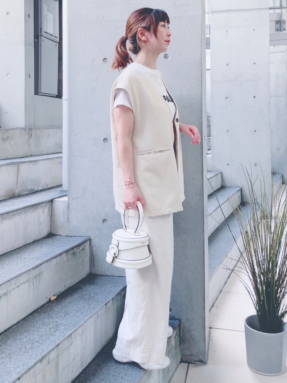 ホワイト系のベスト、ホワイト系のTシャツ/カットソー、ホワイト系のバッグを着用したレディースの秋コーディネートの2枚目の写真