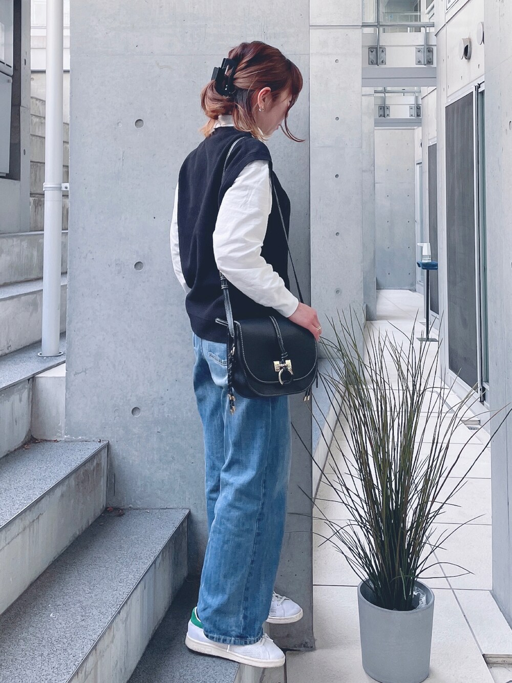 ブルー系のデニムパンツ、ブラック系のショルダーバッグ、ホワイト系のスニーカーを着用したレディースの春コーディネートの3枚目の写真