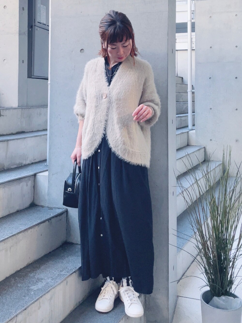 ベージュ系のカーディガン/ボレロ、ブラック系のワンピース、ブラック系のハンドバッグを着用したレディースの冬コーディネートの2枚目の写真