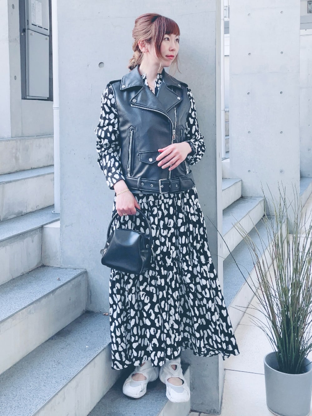 ブラック系のライダースジャケット、ブラック系のワンピース、ブラック系のハンドバッグを着用したレディースの春コーディネートの2枚目の写真