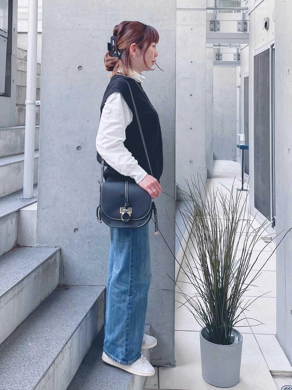 ブルー系のデニムパンツ、ブラック系のショルダーバッグ、ホワイト系のスニーカーを着用したレディースの春コーディネートの2枚目の写真