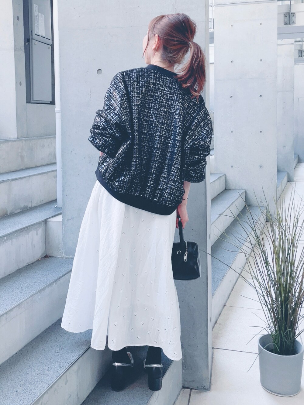 ホワイト系のワンピース、ブラック系のブルゾン、ブラック系のハンドバッグを着用したレディースの春コーディネートの3枚目の写真