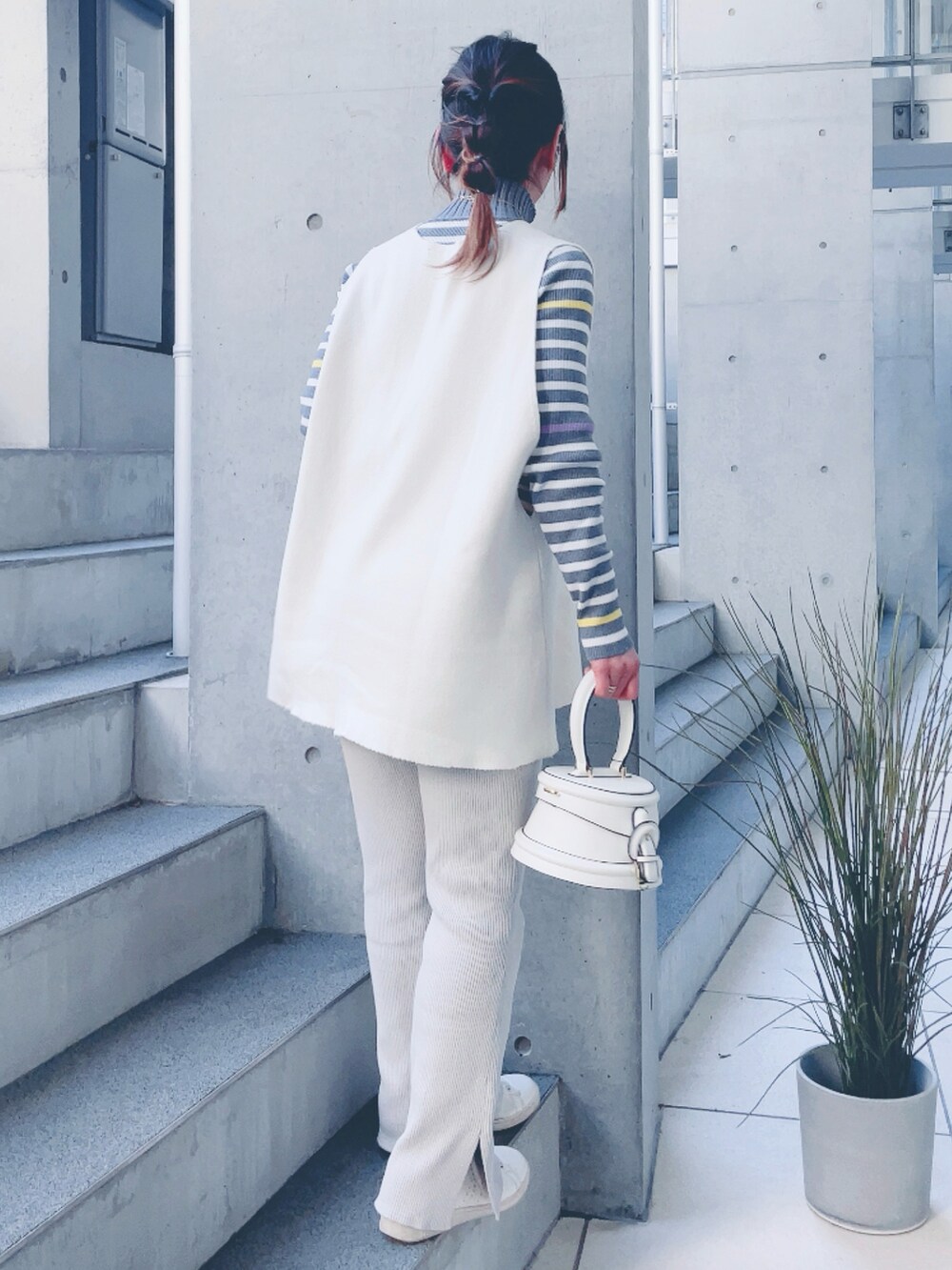 グレー系のニット/セーター、ホワイト系のバッグ、グレー系のスラックスを着用したレディースの冬コーディネートの3枚目の写真