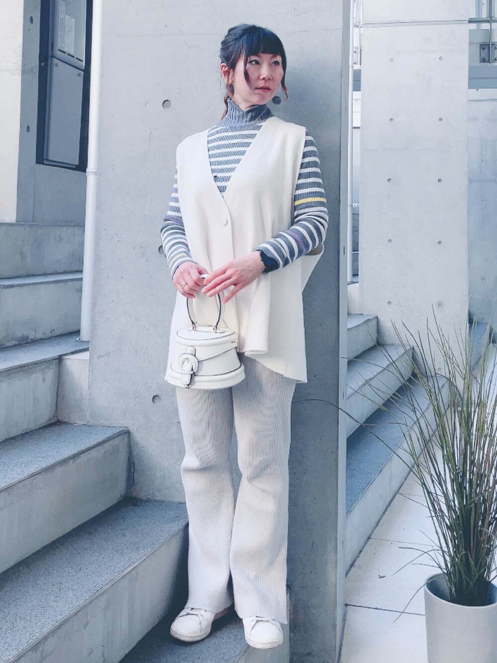 グレー系のニット/セーター、ホワイト系のバッグ、グレー系のスラックスを着用したレディースの冬コーディネートの2枚目の写真