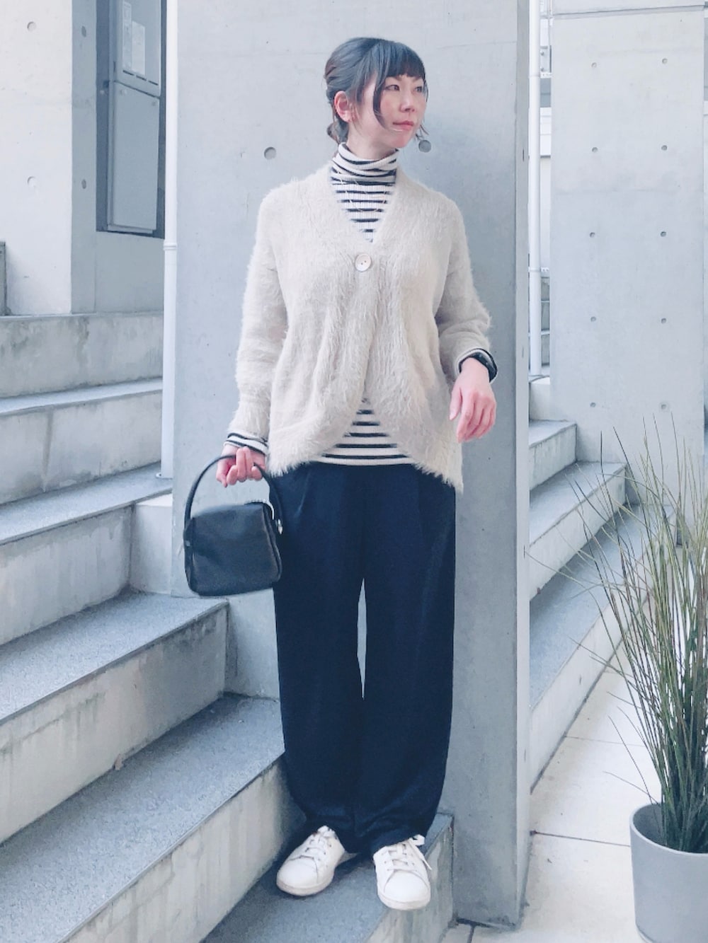 ベージュ系のカーディガン/ボレロ、ブラック系のハンドバッグ、ベージュ系のスニーカーを着用したレディースの冬コーディネートの2枚目の写真