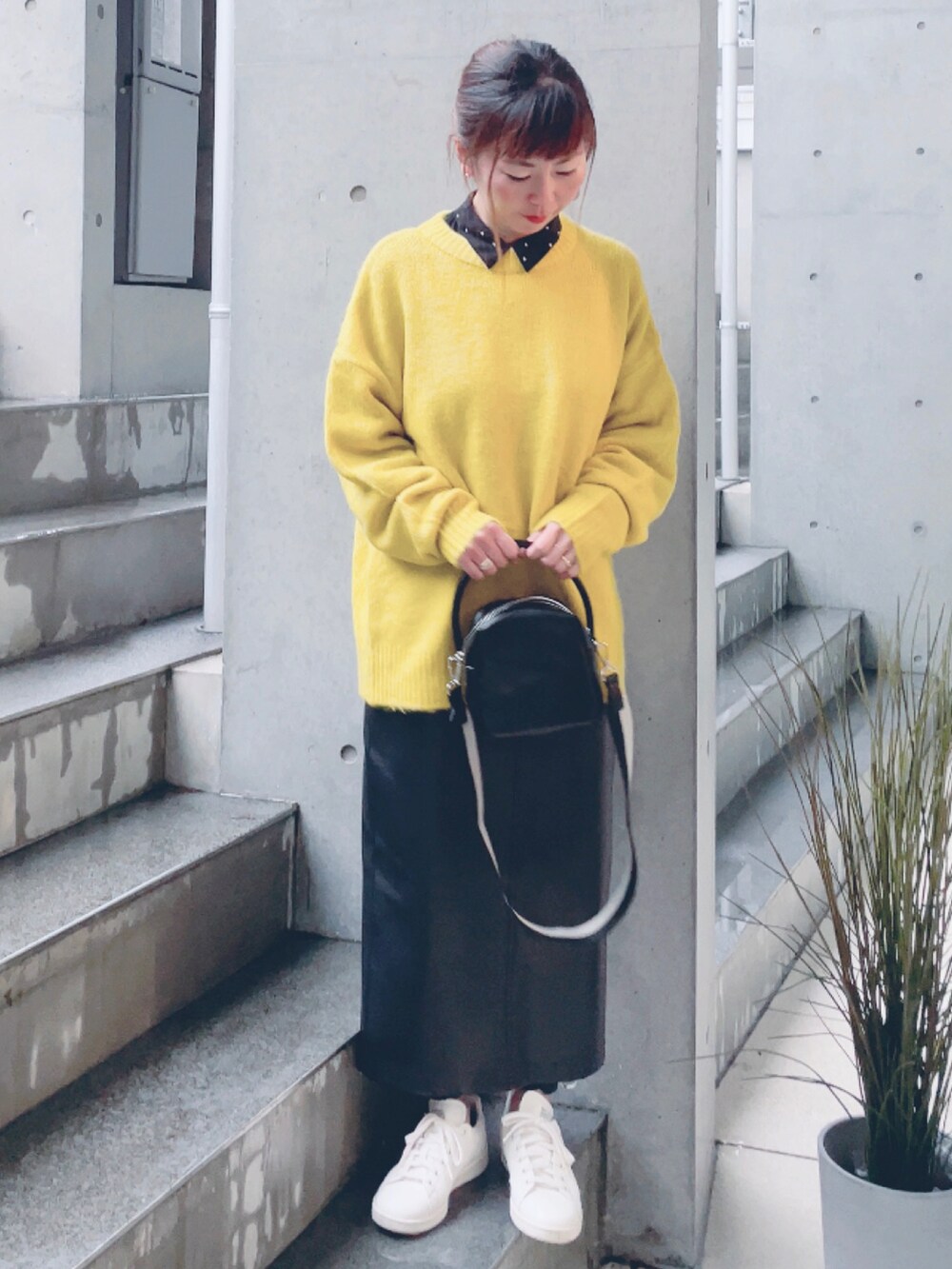イエロー系のニット/セーター、ブラック系のハンドバッグ、ブラック系のスカートを着用したレディースの秋コーディネートの4枚目の写真