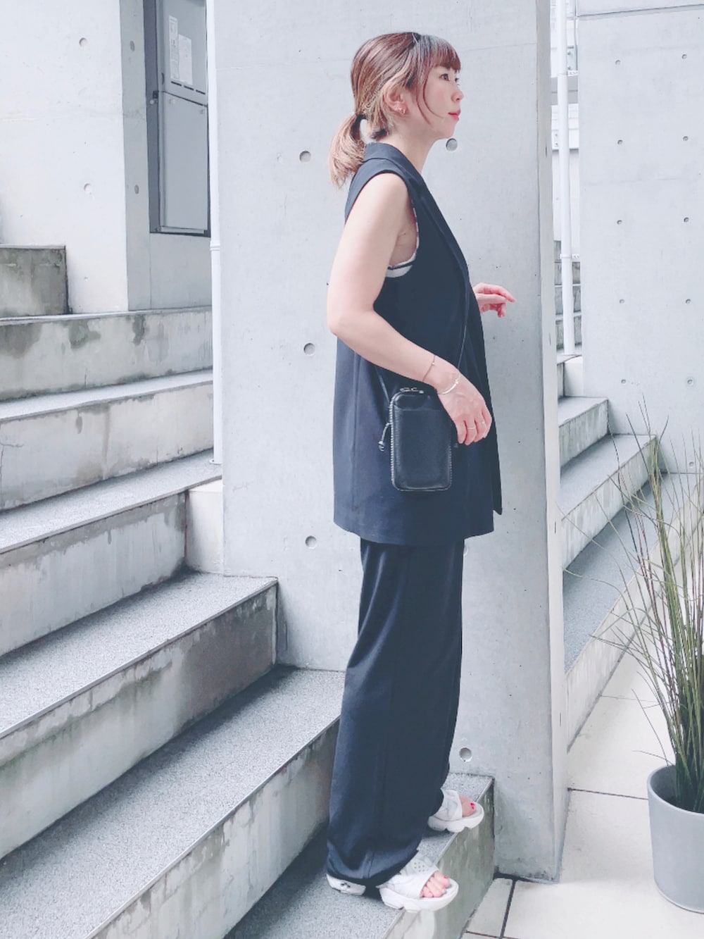 ホワイト系のサンダル、ホワイト系のTシャツ/カットソー、ブラック系のポーチを着用したレディースの秋コーディネートの2枚目の写真