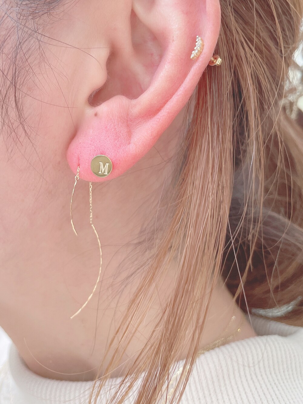 ホワイト系のスウェット、ベージュ系のスカート、ゴールド系のショルダーバッグを着用したレディースの冬コーディネートの5枚目の写真