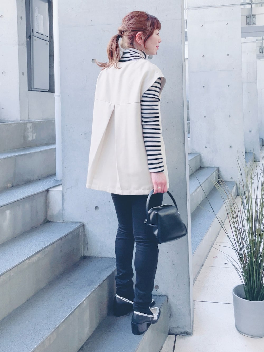 ホワイト系のベスト、ブラック系のハンドバッグ、シルバー系のローファーを着用したレディースの春コーディネートの3枚目の写真