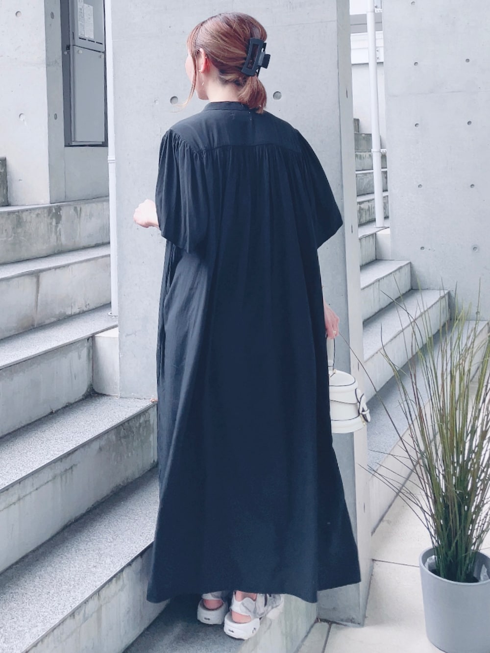 ブラック系のワンピース、ホワイト系のバッグ、ホワイト系のサンダルを着用したレディースの夏コーディネートの3枚目の写真