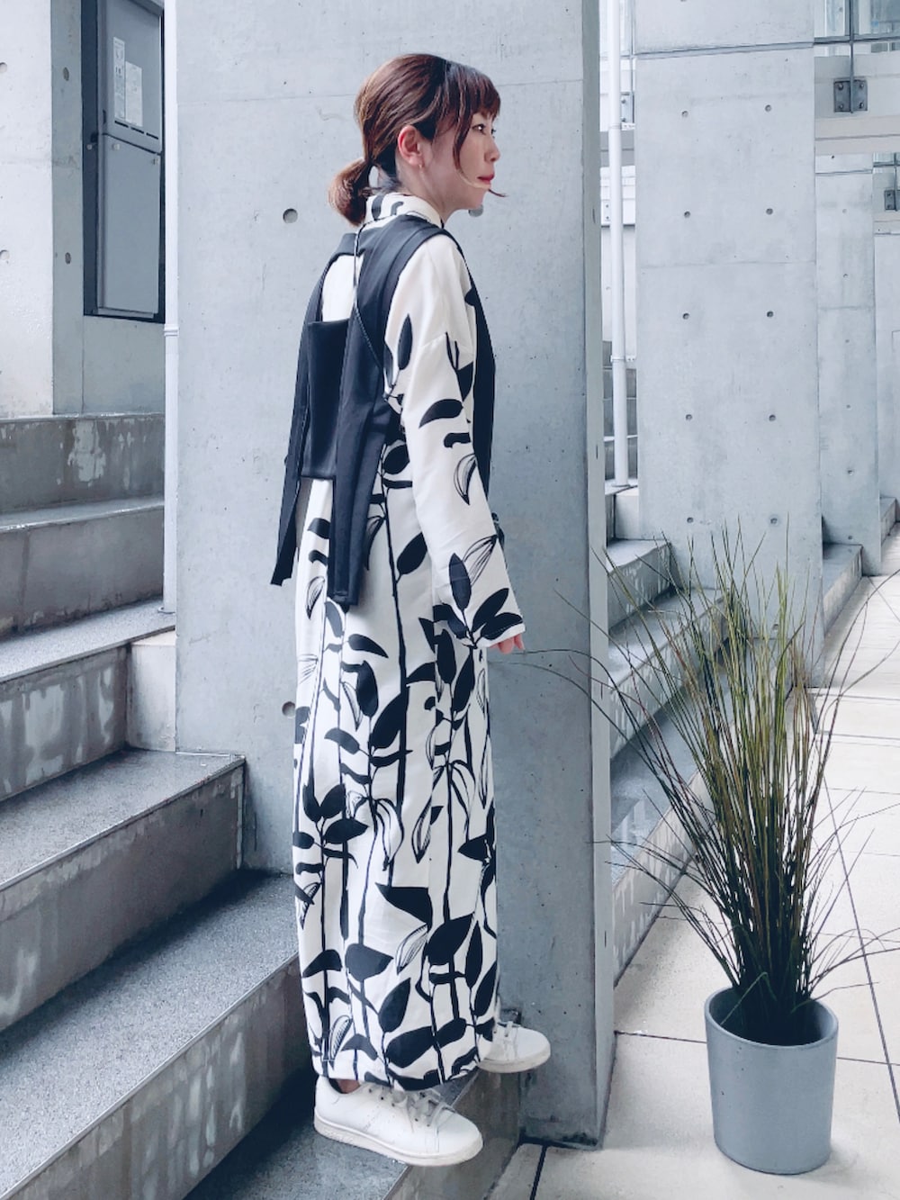 ブラック系のベスト、ホワイト系のシャツワンピース、ベージュ系のスニーカーを着用したレディースの春コーディネートの3枚目の写真