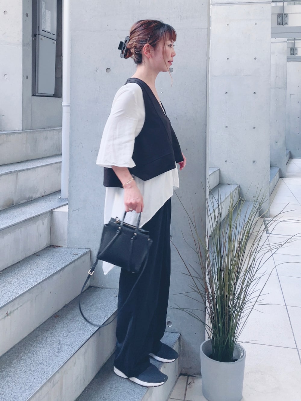 ブラック系のベスト、ホワイト系のシャツ/ブラウス、ブラック系のスニーカーを着用したレディースの秋コーディネートの3枚目の写真