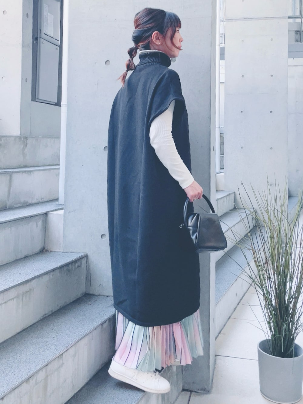 ブラック系のニット/セーター、ブラック系のハンドバッグ、ベージュ系のスニーカーを着用したレディースの秋コーディネートの2枚目の写真