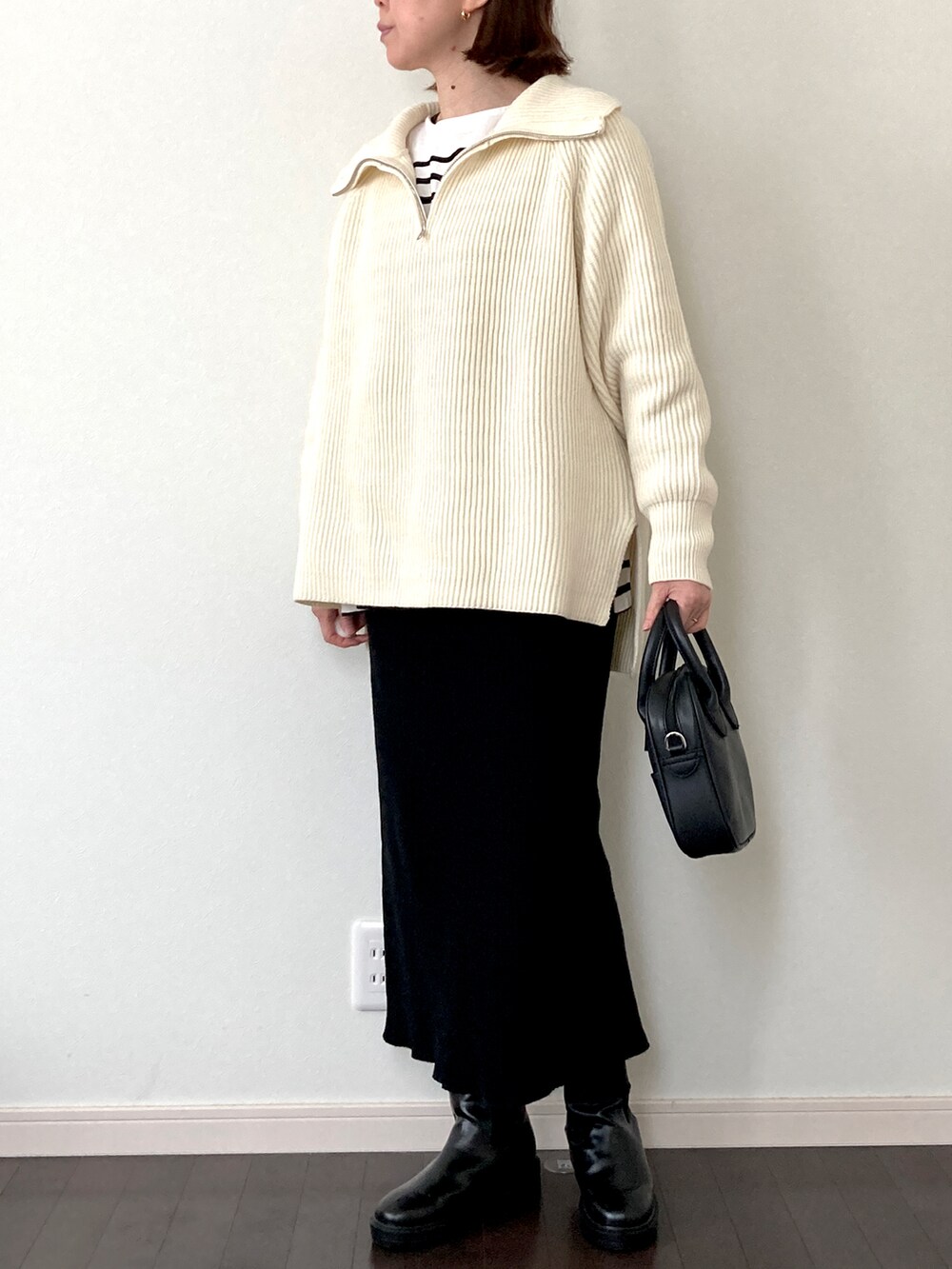 ブラック系のスカート、ホワイト系のTシャツ/カットソー、ブラック系のボストンバッグを着用したレディースの冬コーディネートの2枚目の写真