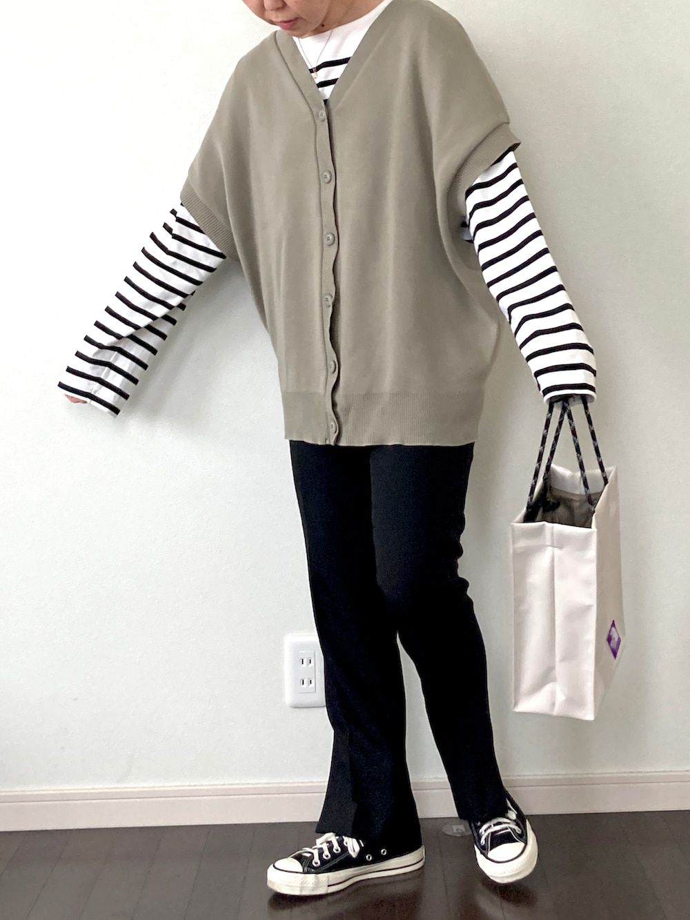 グリーン系のベスト、ホワイト系のTシャツ/カットソー、ホワイト系のトートバッグを着用したレディースの冬コーディネートの2枚目の写真