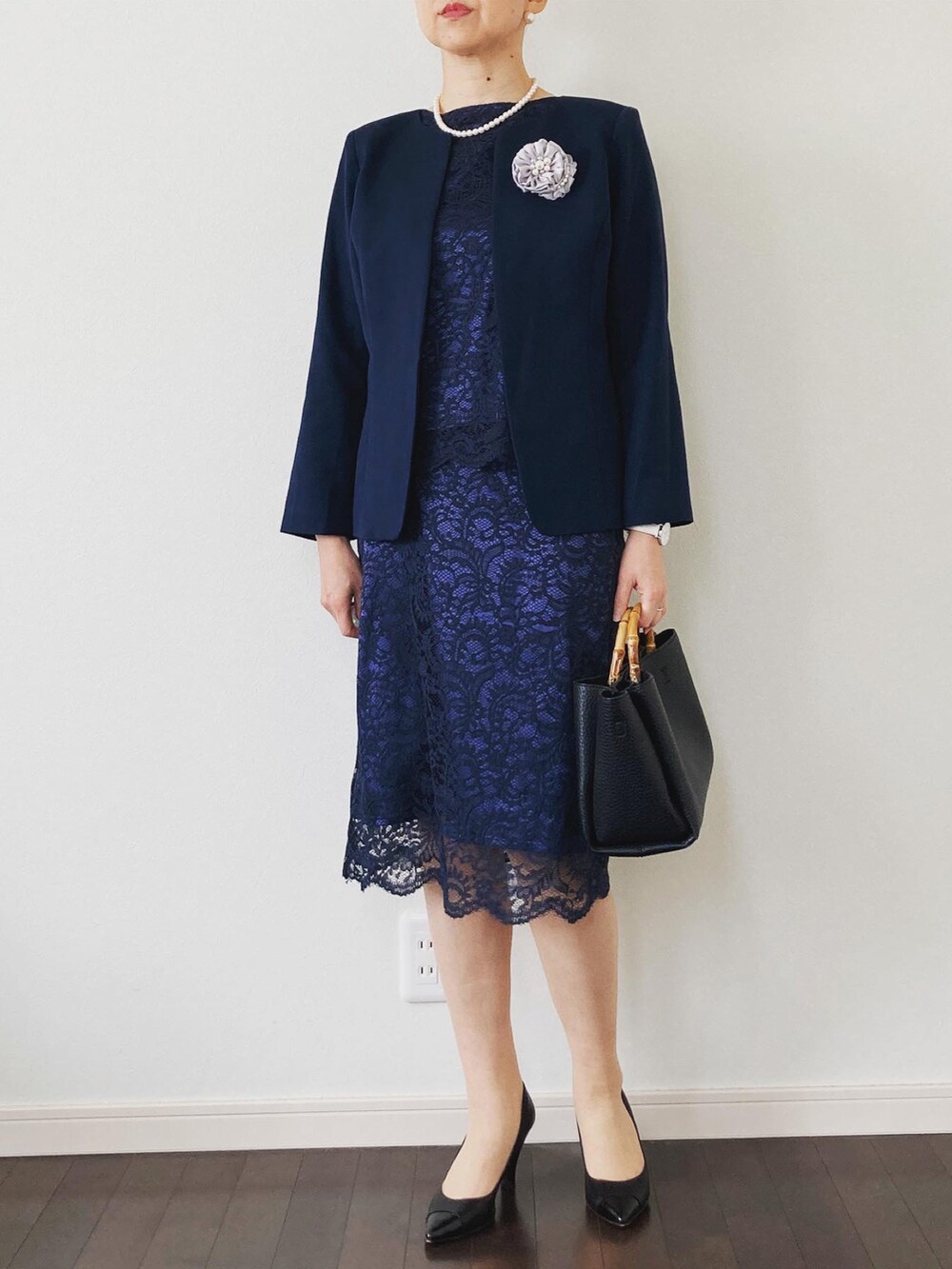 ブルー系のスーツセット、ベージュ系のショルダーバッグ、ブラック系のパンプスを着用したレディースの冬コーディネートの2枚目の写真