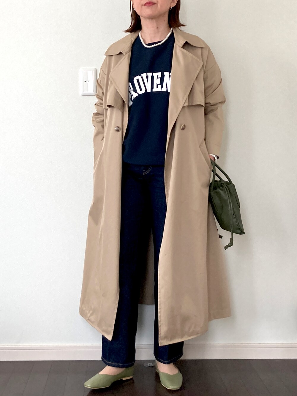 ブルー系のデニムパンツ、ベージュ系のトレンチコート、ブルー系のTシャツ/カットソーを着用したレディースの冬コーディネートの2枚目の写真