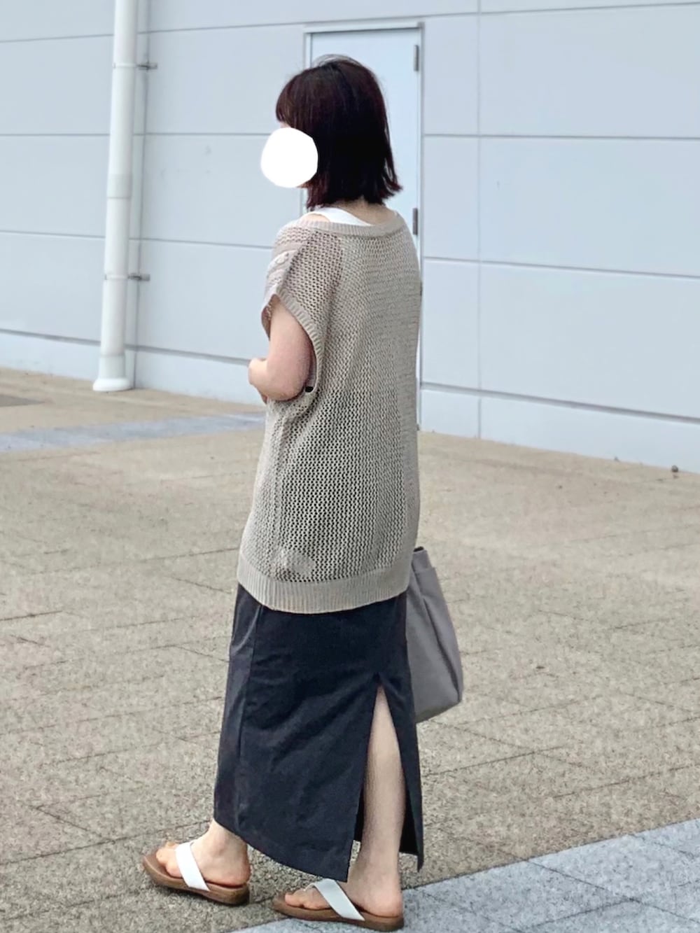 ホワイト系のサンダル、グレー系のスカート、ベージュ系のベストを着用したレディースの夏コーディネートの2枚目の写真
