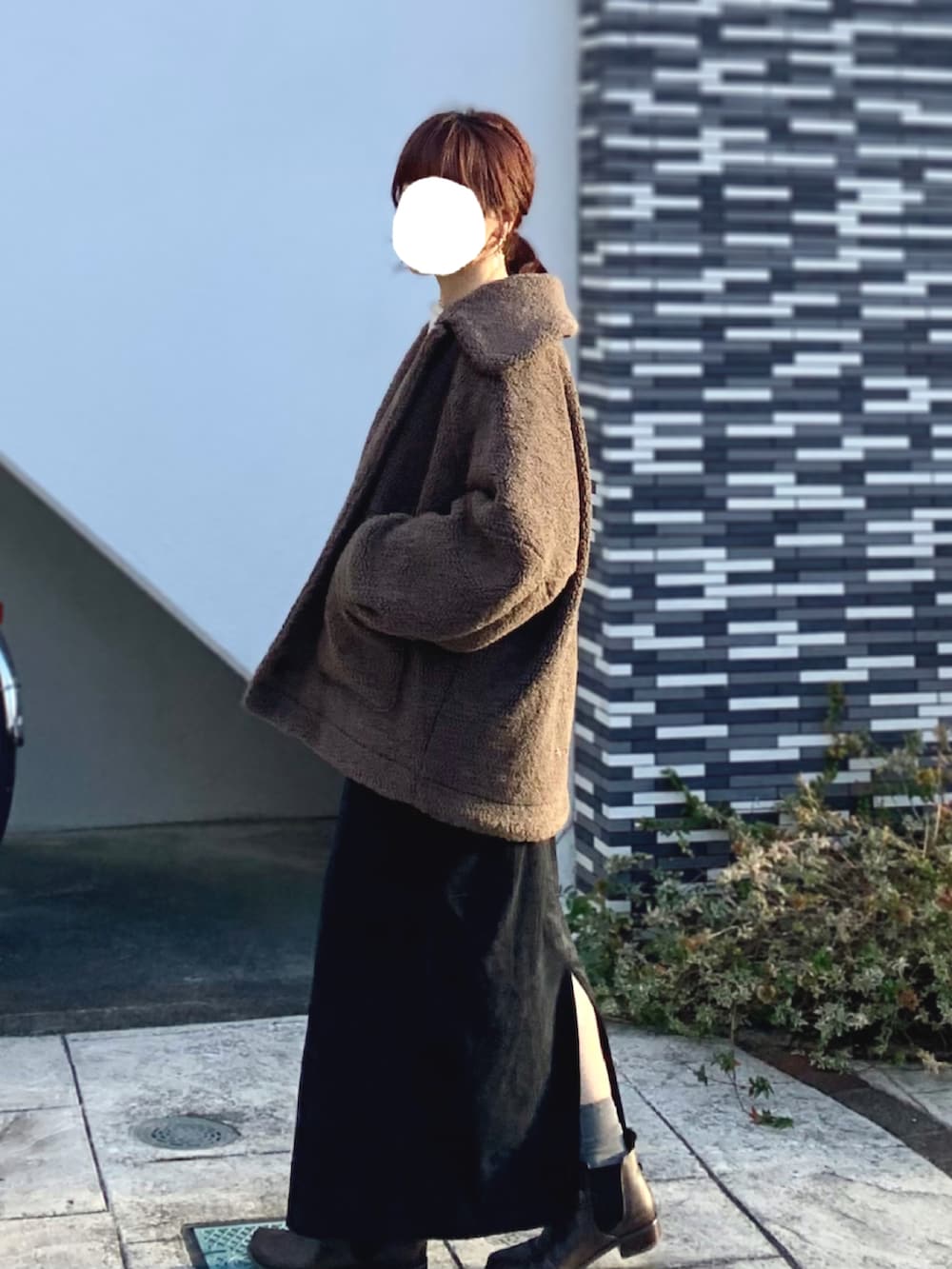 ブラウン系のブルゾン、ブラック系のジャンパースカート、ホワイト系のニット/セーターを着用したレディースの冬コーディネートの2枚目の写真