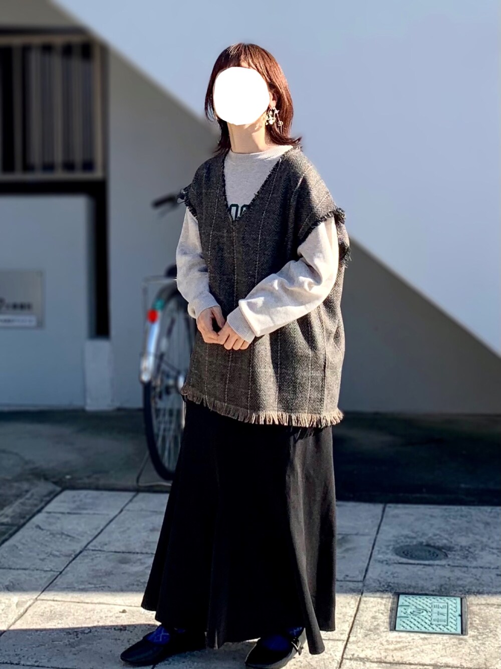 ブラック系のスカート、グレー系のベスト、ホワイト系のニット/セーターを着用したレディースの秋コーディネートの2枚目の写真