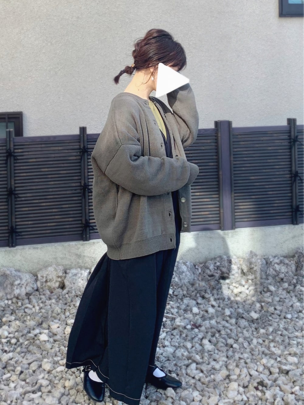 ブラック系のパンプス、ブラック系のジャンパースカート、グリーン系のカーディガン/ボレロを着用したレディースの春コーディネートの2枚目の写真