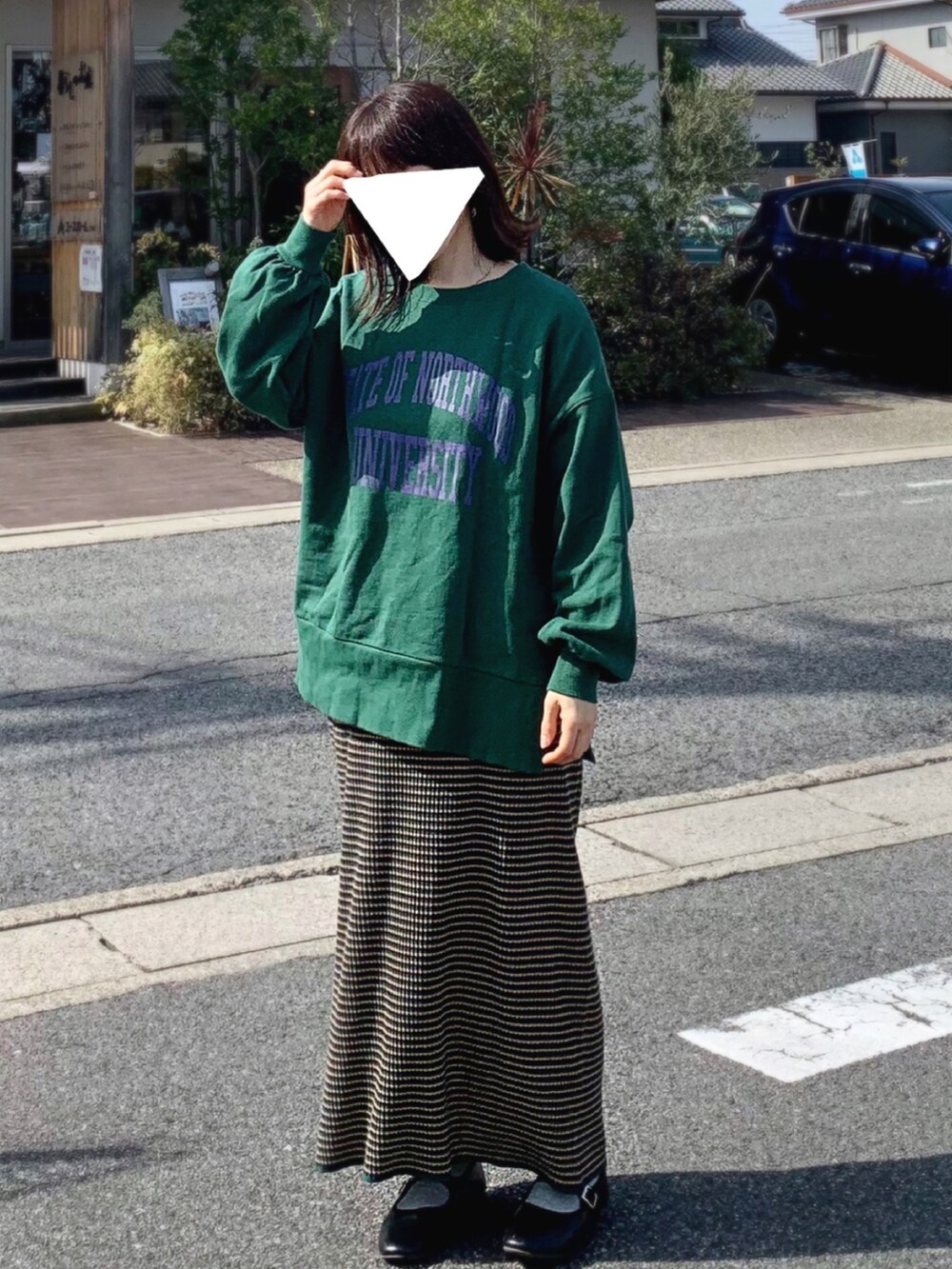 グリーン系のスウェット、グリーン系のスカート、ブラック系のパンプスを着用したレディースの春コーディネートの2枚目の写真