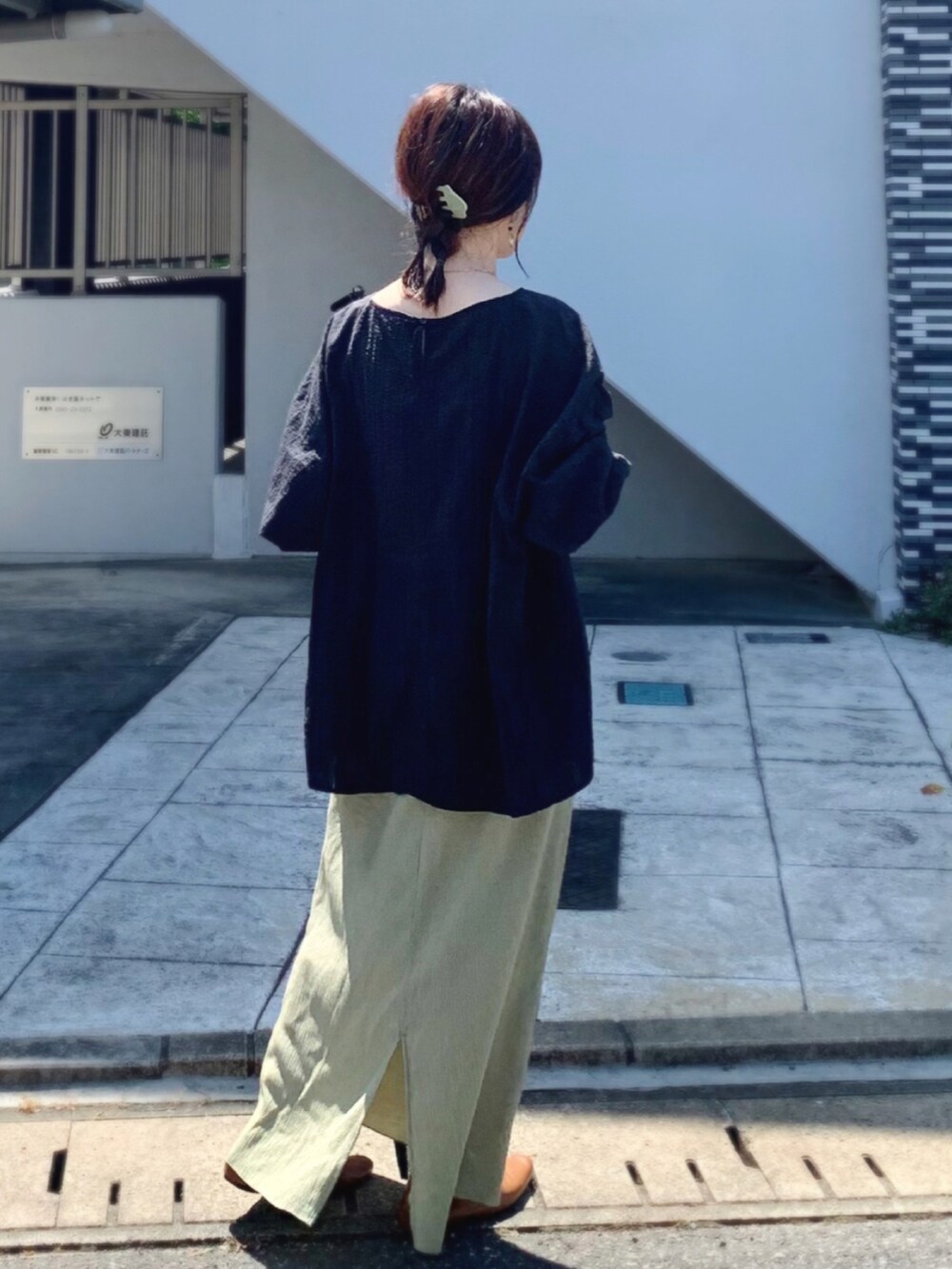 ブラック系のトップス、グリーン系のスカート、ブラウン系のパンプスを着用したレディースの夏コーディネートの2枚目の写真