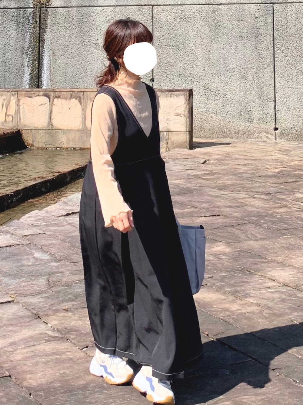 ブラック系のジャンパースカート、ベージュ系のスニーカー、ベージュ系のTシャツ/カットソーを着用したレディースの夏コーディネートの2枚目の写真