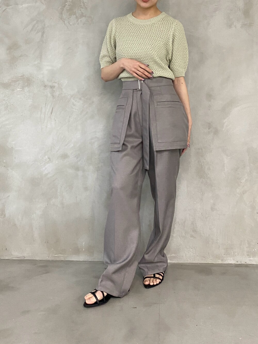 グリーン系のニット/セーター、グレー系のスラックスを着用したレディースの春コーディネートの2枚目の写真