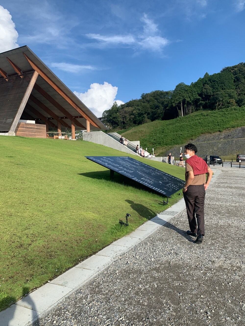 ブラウン系のポロシャツ、レッド系のカーディガン/ボレロ、ブラウン系のスラックスを着用したメンズの秋コーディネートの2枚目の写真