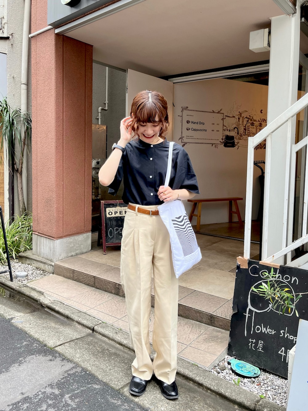 ホワイト系のトートバッグ、ブラック系のシャツ/ブラウス、ベージュ系のパンツを着用したレディースの春コーディネートの3枚目の写真