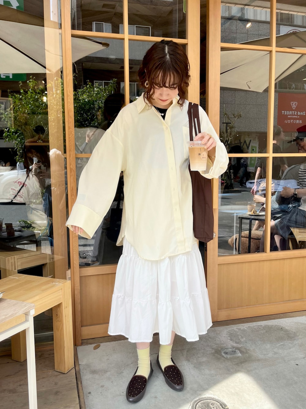 イエロー系のシャツ/ブラウス、ホワイト系のスカート、ブラウン系のバッグを着用したレディースの春コーディネートの5枚目の写真