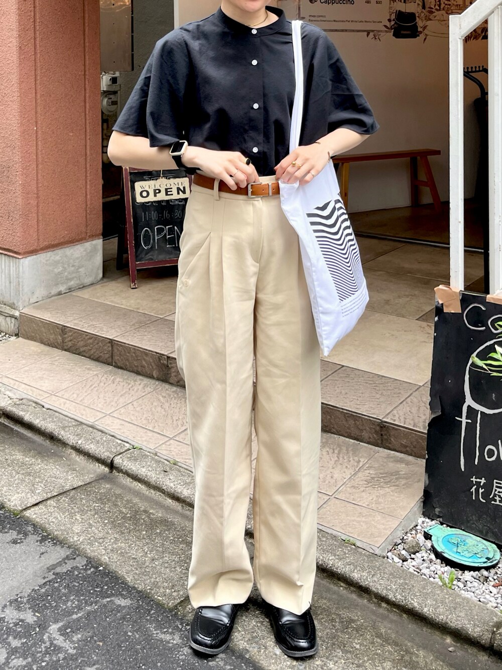 ホワイト系のトートバッグ、ブラック系のシャツ/ブラウス、ベージュ系のパンツを着用したレディースの春コーディネートの2枚目の写真