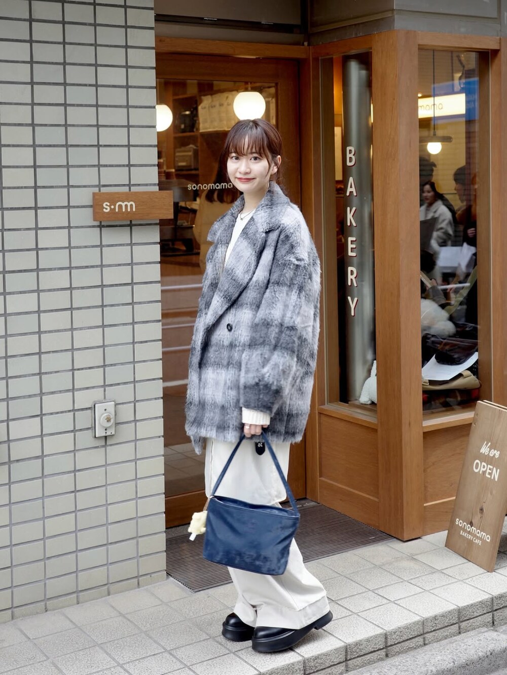 ホワイト系のトップス、ホワイト系のパンツ、ブルー系のバッグを着用したレディースの春コーディネートの3枚目の写真