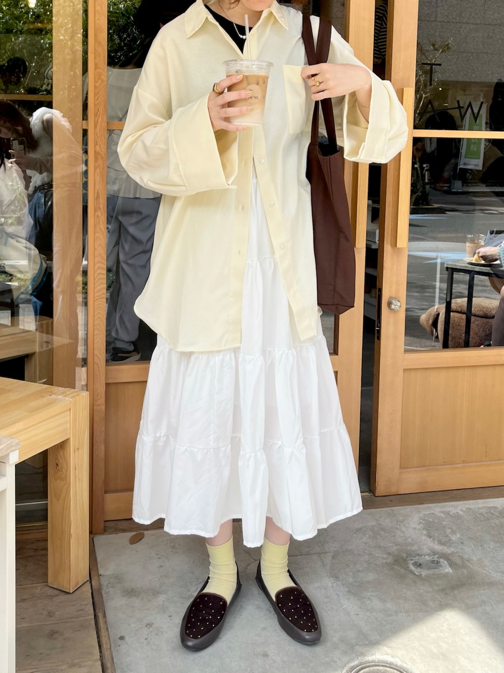 イエロー系のシャツ/ブラウス、ホワイト系のスカート、ブラウン系のバッグを着用したレディースの春コーディネートの3枚目の写真