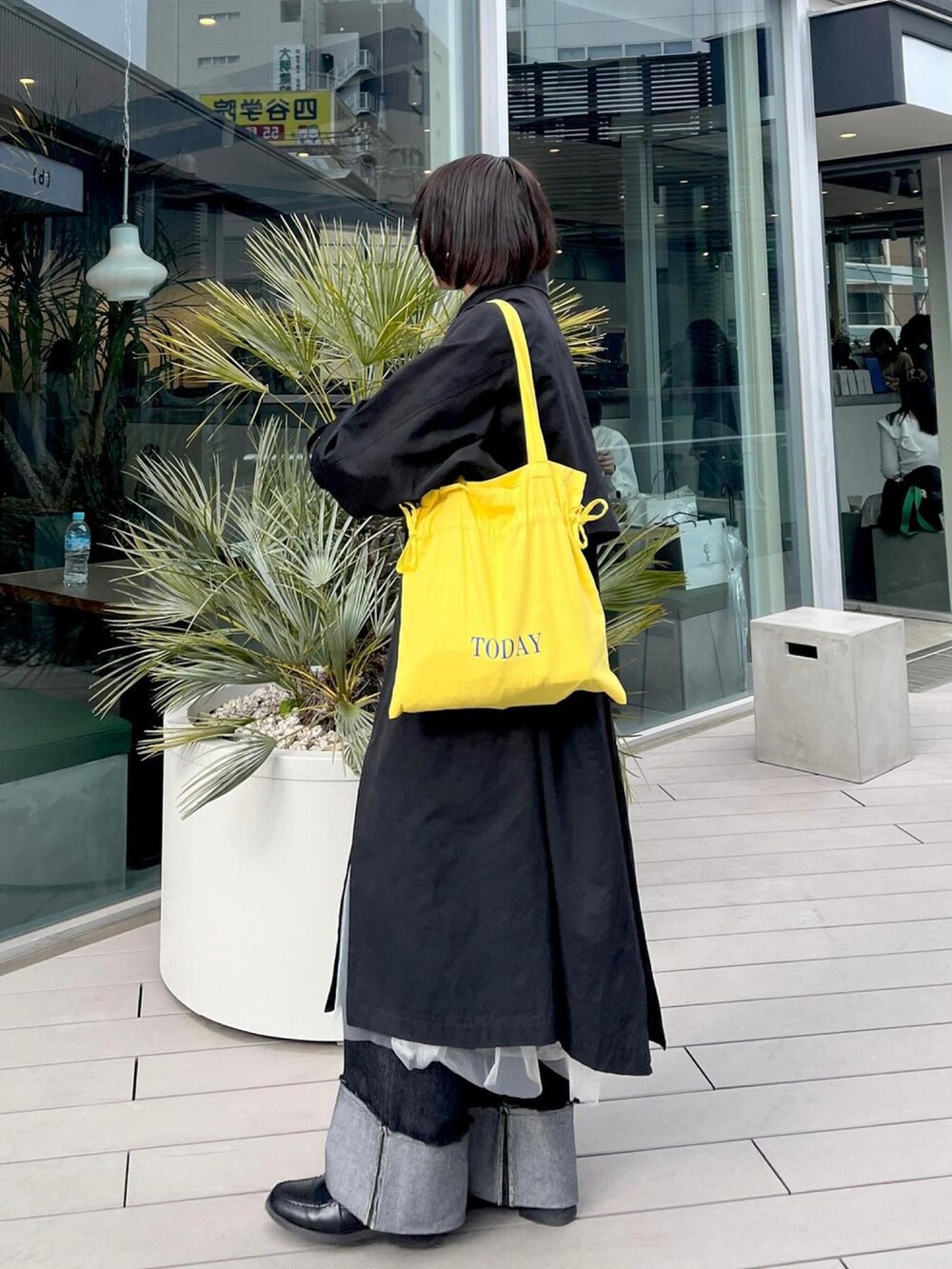 イエロー系のトートバッグ、ブラック系のローファー、ブラック系のデニムパンツを着用したレディースの春コーディネートの3枚目の写真