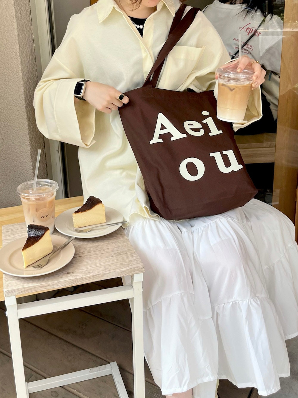 イエロー系のシャツ/ブラウス、ホワイト系のスカート、ブラウン系のバッグを着用したレディースの春コーディネートの2枚目の写真