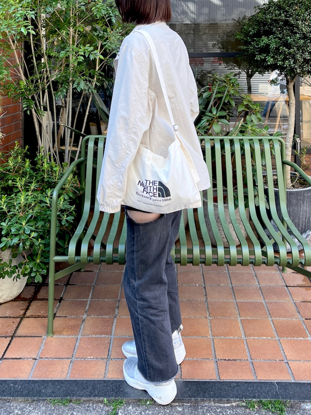 シルバー系のスリッポン、ブラック系のデニムパンツ、ホワイト系のキャミソールを着用したレディースの春コーディネートの2枚目の写真