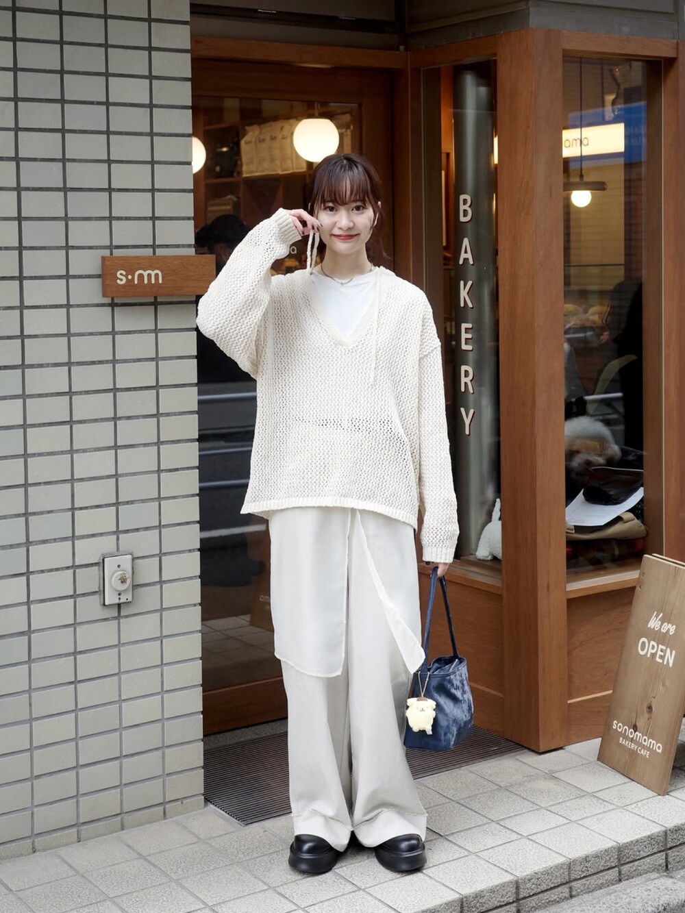 ホワイト系のトップス、ホワイト系のパンツ、ブルー系のバッグを着用したレディースの春コーディネートの2枚目の写真
