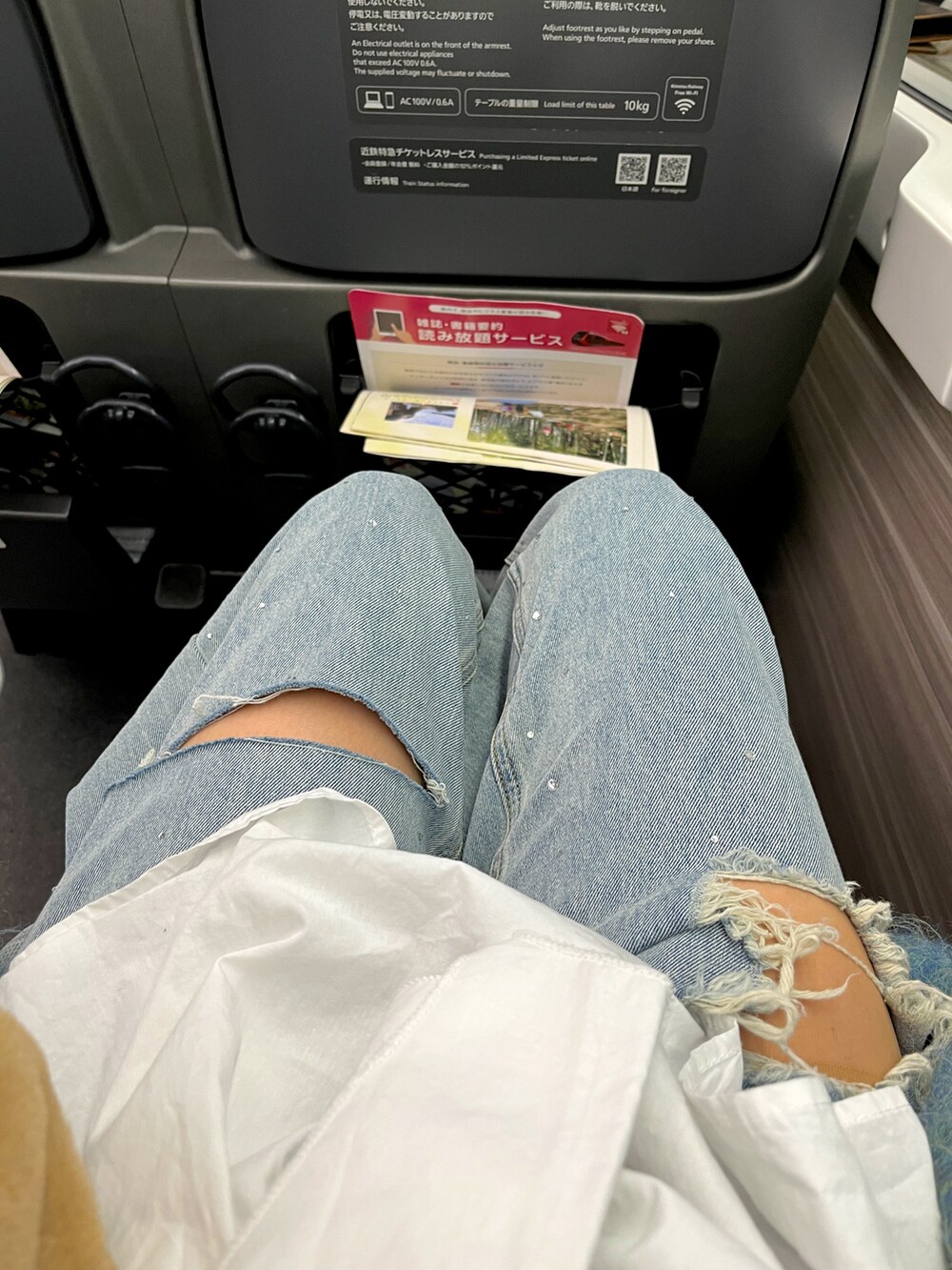 ホワイト系のチュニック、ブルー系のカーディガン/ボレロ、ベージュ系のスニーカーを着用したレディースの春コーディネートの2枚目の写真