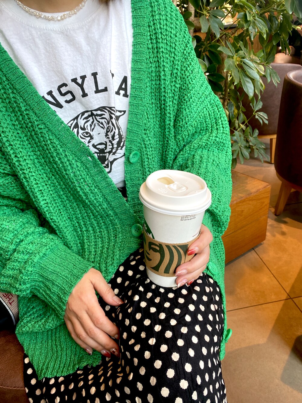 ブラック系のスカート、グリーン系のカーディガン/ボレロ、ホワイト系のTシャツ/カットソーを着用したレディースの春コーディネートの2枚目の写真