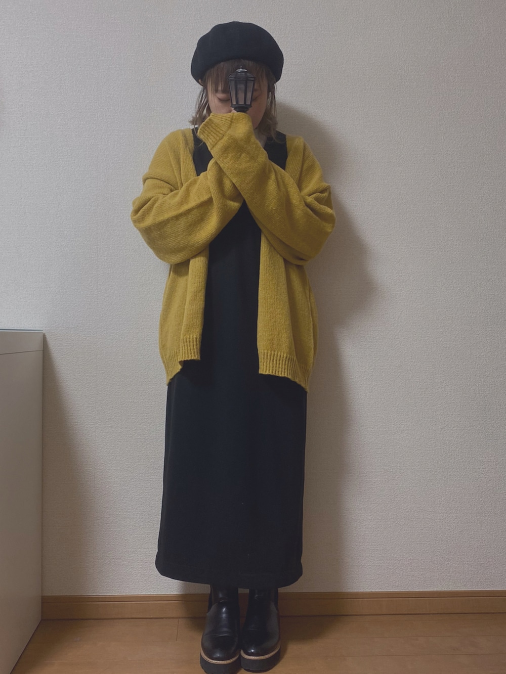 イエロー系のカーディガン/ボレロ、ブラック系のスカート、ブラック系のブーツを着用したレディースの冬コーディネートの2枚目の写真