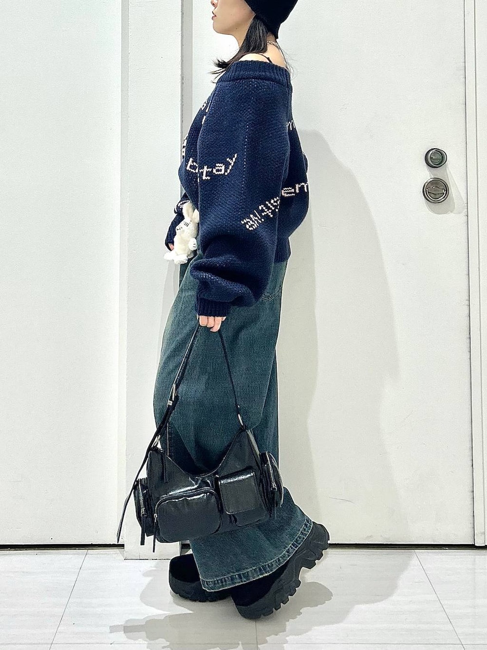 ブルー系のデニムパンツ、ブラック系のショルダーバッグ、ブルー系のニット/セーターを着用したレディースの秋コーディネートの6枚目の写真
