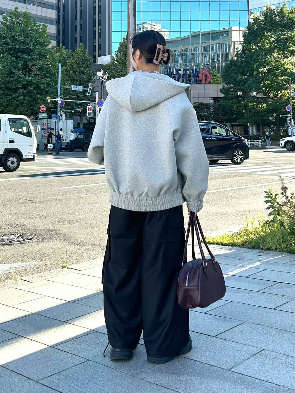 グレー系のパーカー、レッド系のボストンバッグ、ブラック系のスラックスを着用したレディースの秋コーディネートの5枚目の写真