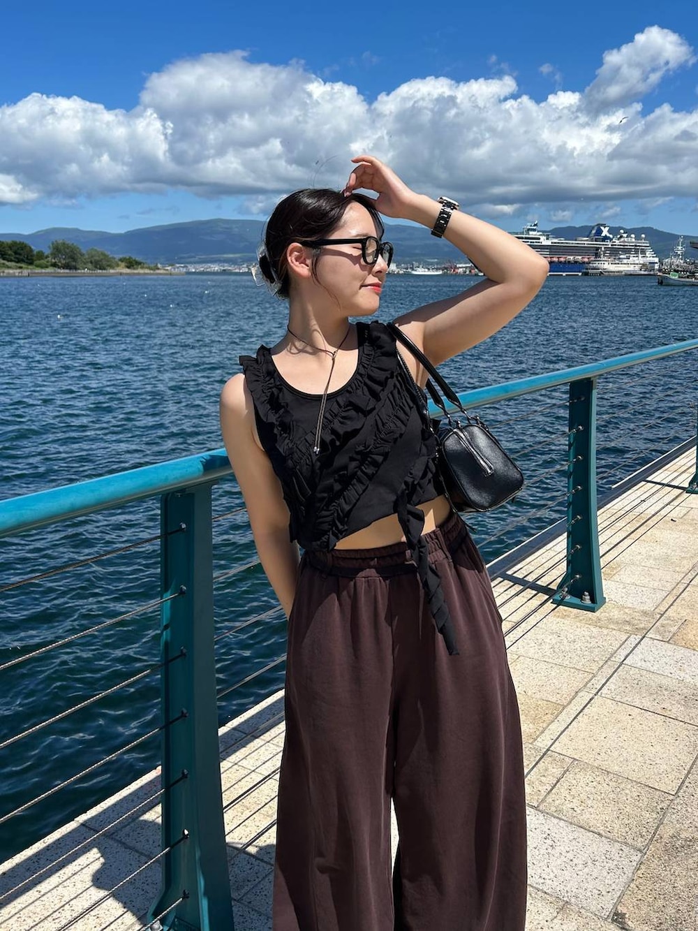 ブラック系のスニーカー、ブラック系のボストンバッグ、ブラウン系のスウェットパンツを着用したレディースの夏コーディネートの4枚目の写真