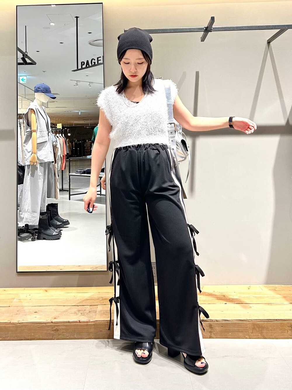 ブラック系のサンダル、ホワイト系のベスト、ブラック系のキャミソールを着用したレディースの夏コーディネートの2枚目の写真