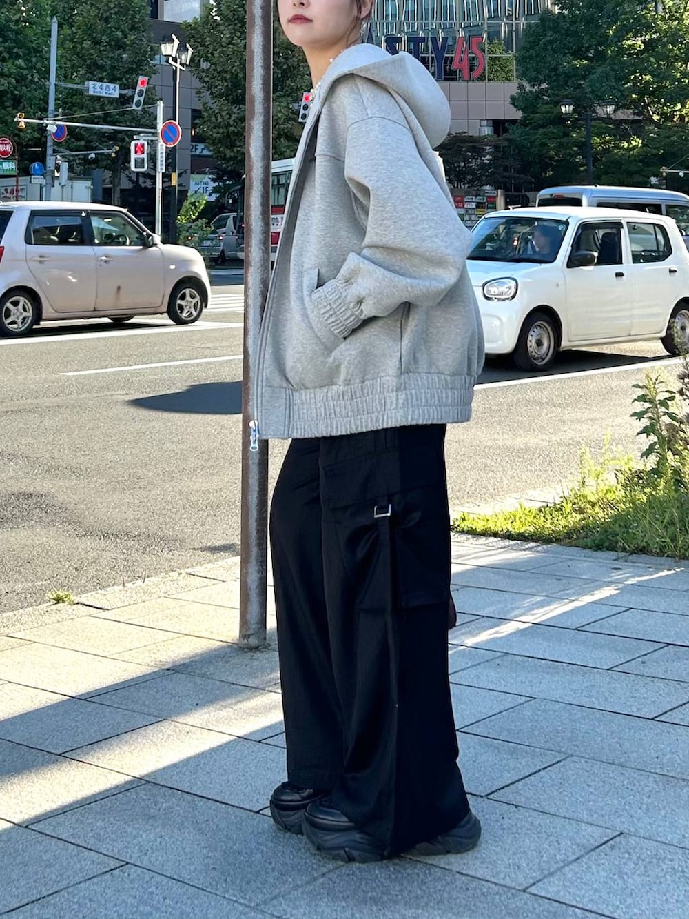 グレー系のパーカー、レッド系のボストンバッグ、ブラック系のスラックスを着用したレディースの秋コーディネートの7枚目の写真