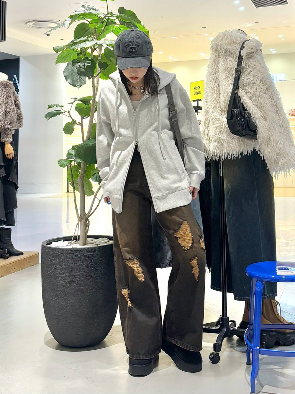 ブラック系のショルダーバッグ、グレー系のパーカー、ブラック系のブーツを着用したレディースの冬コーディネートの2枚目の写真