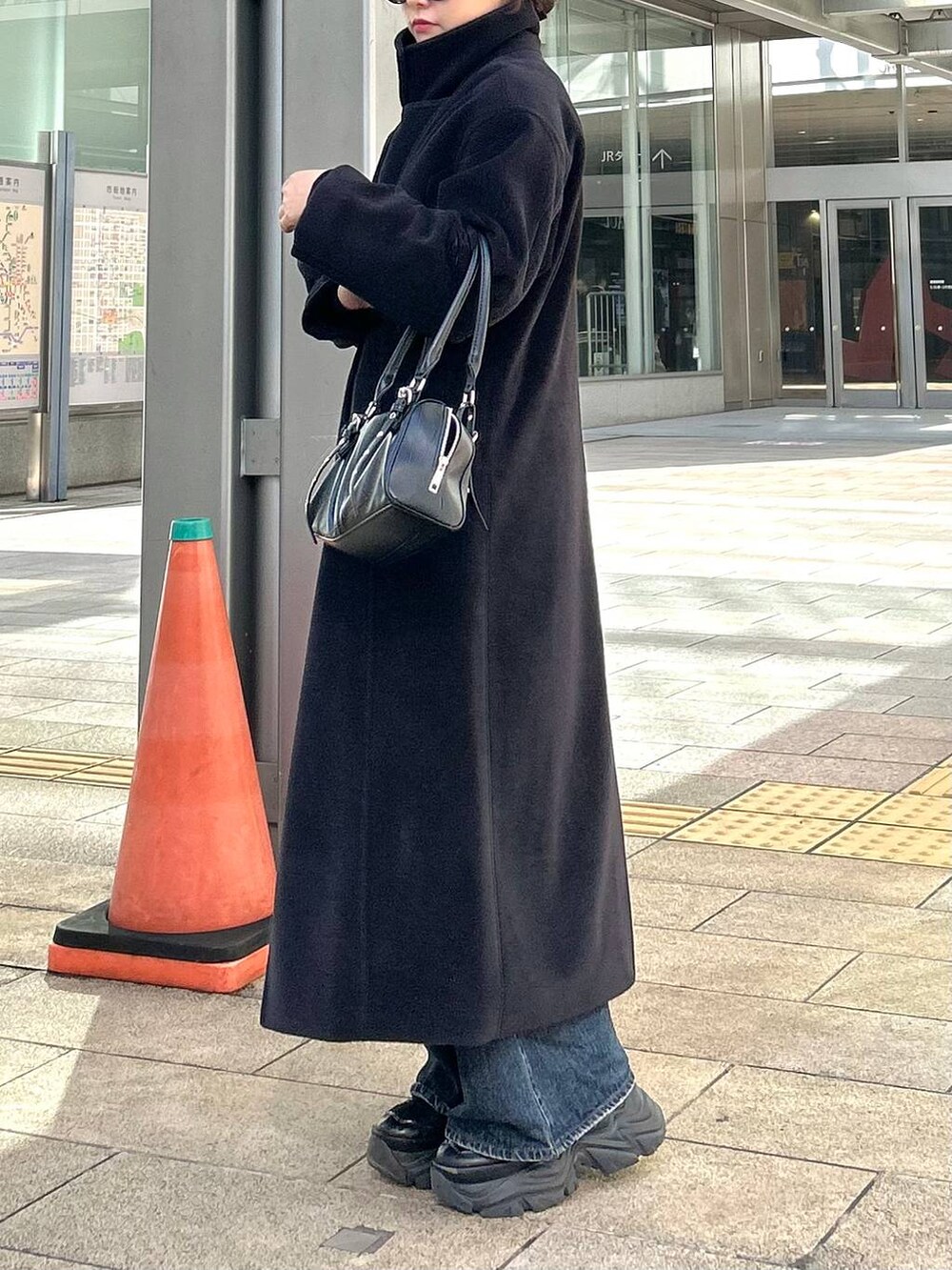 ブラック系のスニーカー、ブルー系のデニムパンツ、ブラック系のボストンバッグを着用したレディースの秋コーディネートの3枚目の写真